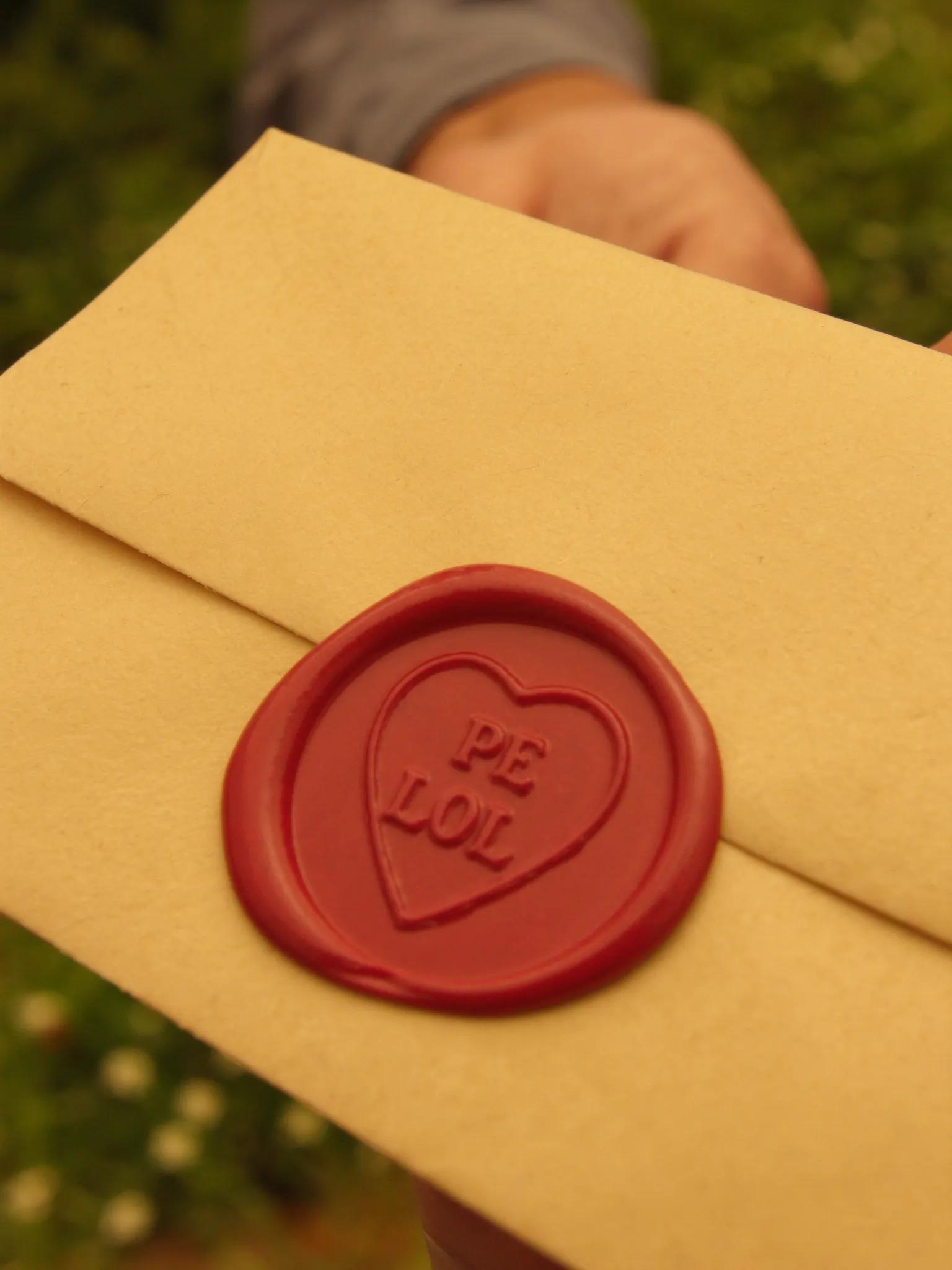 Mão entregando carta com selo dourado